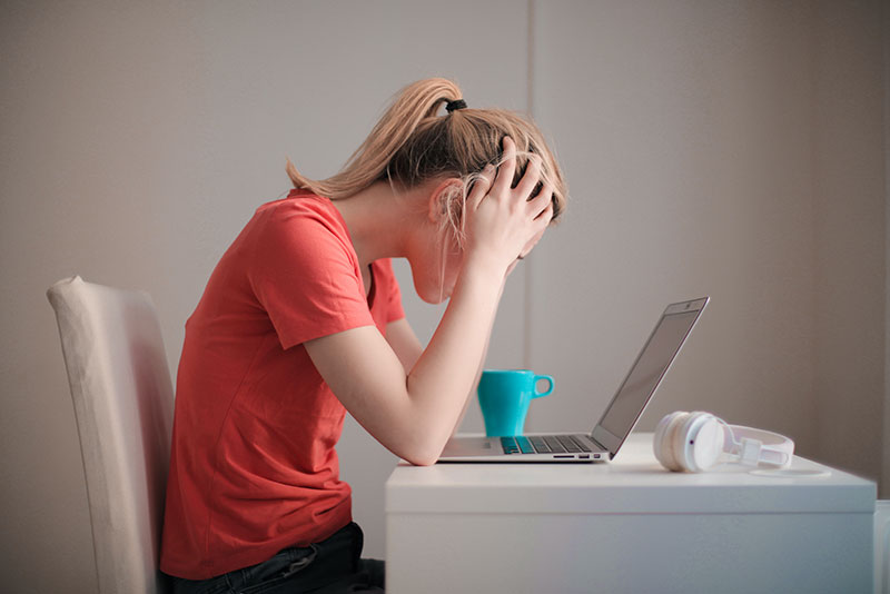 mental-health-foundation-blog-post-what-it-is-like-to-live-with-severe-anxiety-photograph-of-woman-holding-head-sitting-at-computer