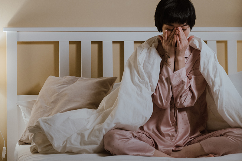 mental health foundation articles loneliness image of a woman sitting in bed looking overwhelmed